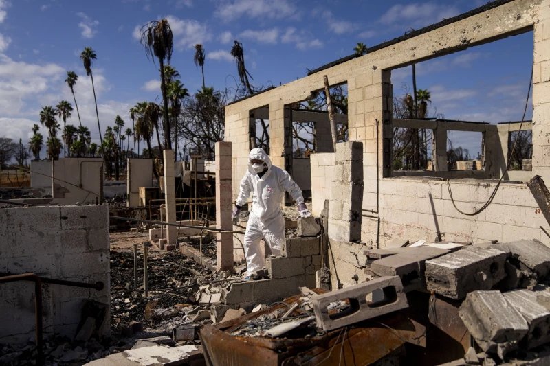 The Rev. Ai Hironaka, resident minister of the Lahaina Hongwanji Mission, walks through the grounds of his temple and residence destroyed by wildfire, Dec. 7, 2023, in Lahaina, Hawaii.