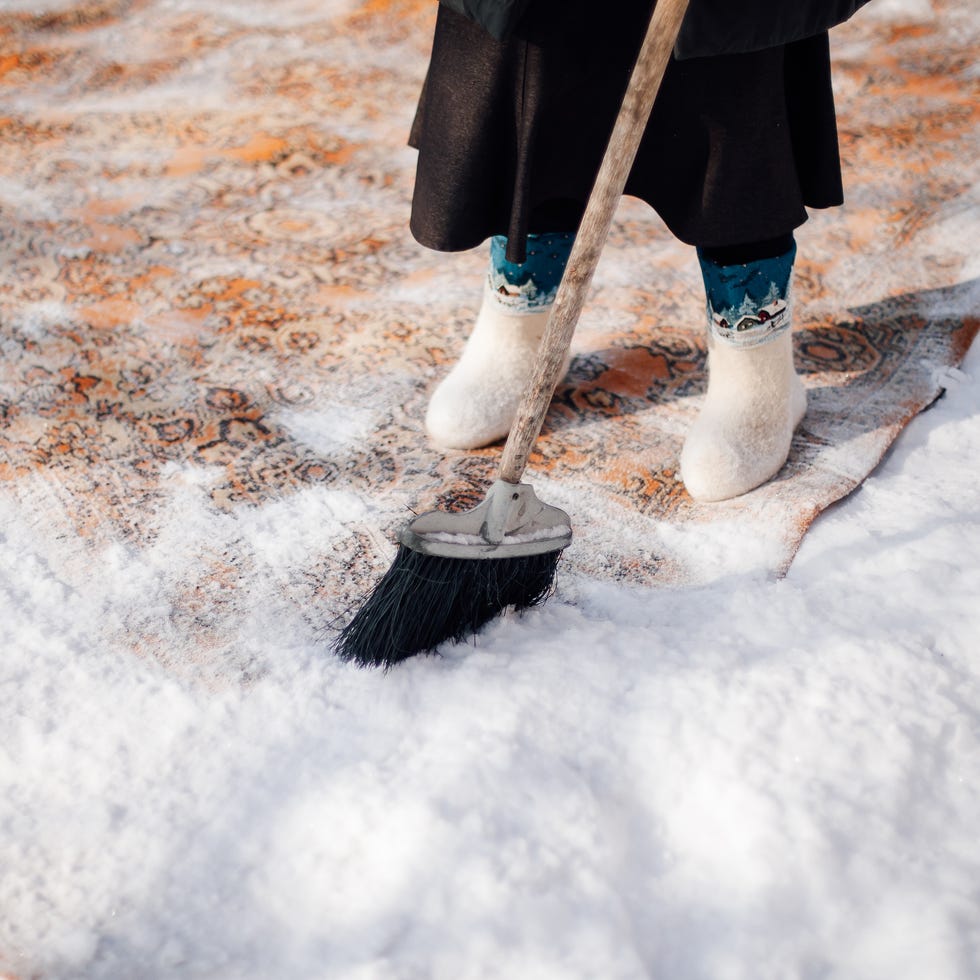 Cleaning a rug outside with snow (Iuliia Burmistrova//Getty Images)