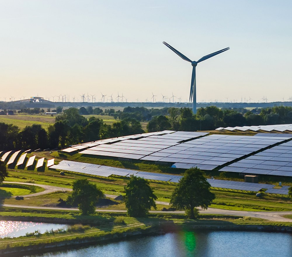 Solar panels and wind turbines near a pond (iStock)
